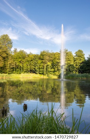 Pond with huge fountain in a park in the morning light