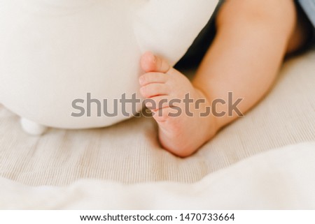 Partial View of Cute Baby Leg Sleeping in Bed. Closeup Picture of Cute Infant Small Foot on Plain Beige Blanket. Peaceful New Born Little Kid Lying. Caucasian Toddler Napping Natural Light