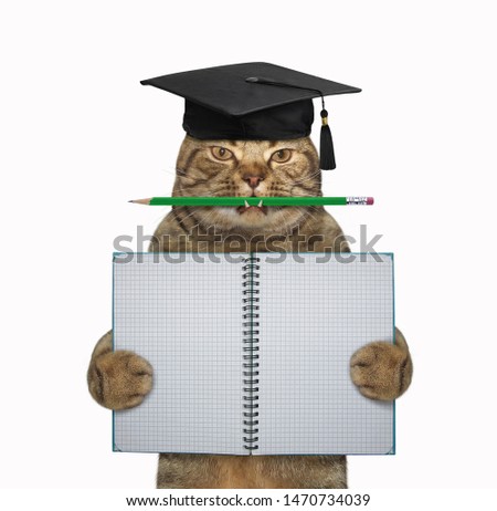 The cat teacher in a square academic hat with a pencil in his mouth is holding a school blank open notebook. White background. Isolated.