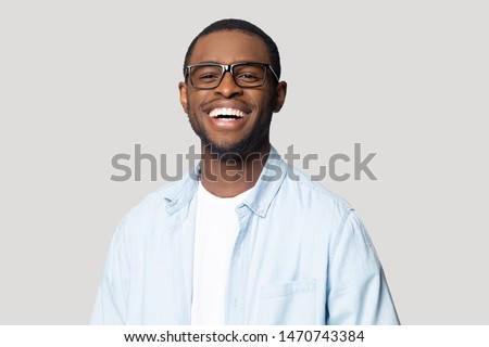 Joyful happy african american young man in eyeglasses portrait. Isolated on grey studio background smiling millennial black guy looking at camera, laughing, having fun, posing for photo head shot.