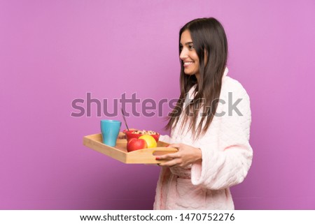 Young woman in pajamas and dressing gown over isolated purple background