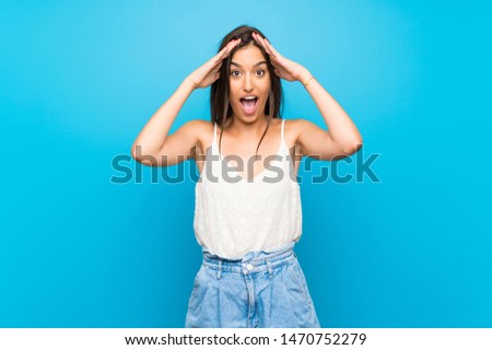 Young woman over isolated blue background with surprise expression