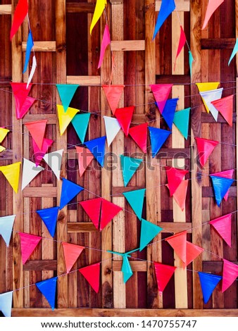Colourful small triangular flags tied together with rope against Thai brick pattern wooden wall, decoration in Thai traditional temple fair culture festival