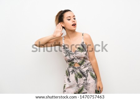 Young woman over isolated white background listening to something by putting hand on the ear