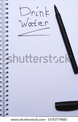Notebook and glass of water on white table