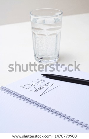 Notebook and glass of water on white table