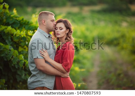 couple of people man and woman 30-39 years old in the vineyards in summer at sunset kiss