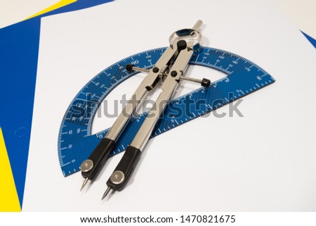Protractor and Compass on notebook paper. White background. 