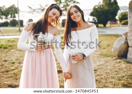 Beautiful girls in a park. Friends have fun in a summer city. Ladies with a cocktails