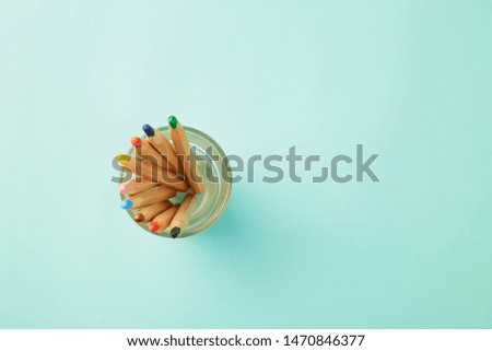 Flat lay photo, Colorful Crayon in glass on pastel pale blue background, World Teachers' Day or Back to school concept , copy space for text