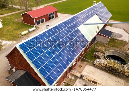 Top view of blue solar photo voltaic panels system on wooden building, barn or house roof. Renewable ecological green energy production concept.