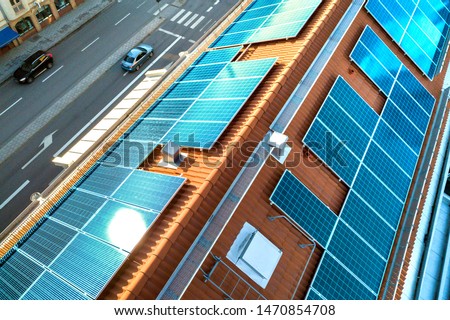 Top view of blue solar photo voltaic panels system on high apartment building roof top on sunny day. Renewable ecological green energy production concept. Royalty-Free Stock Photo #1470854708