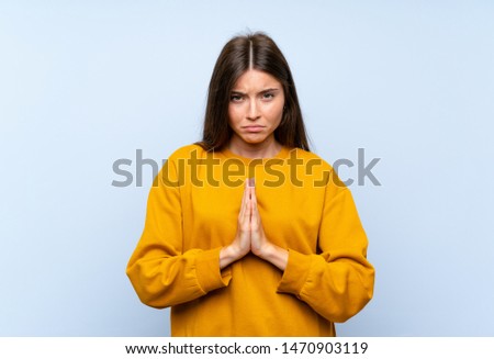 Caucasian young woman over isolated blue wall pleading
