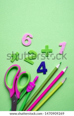 Colored different school supplies on light green paper background. Back to school concept. Flat lay, top view, copy space