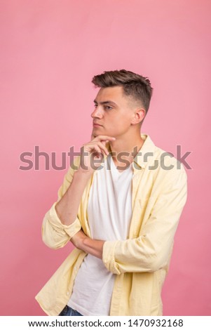 Young man thinking about things. Cropped shot of thoughtful young man standing near pink background