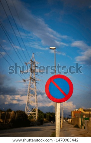 Parking forbidden sign from Spain on a cloudy day with high voltage tower in the background with copy space