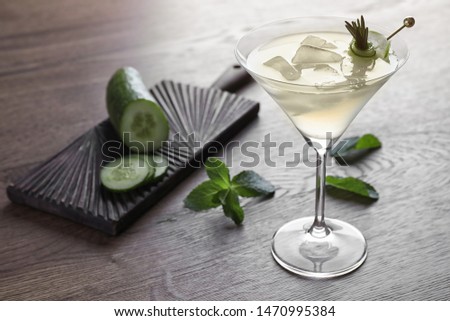 Glass of tasty cucumber martini and ingredients on wooden table