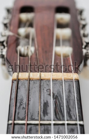 Focus on the nut and strings of a acoustic guitar headstock. Old acoustic guitar, worn out and dusty.