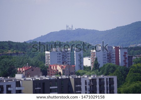 view of the modern city on the hills, stone buildings. different style houses in the distance. city with lots of greenery, tall trees