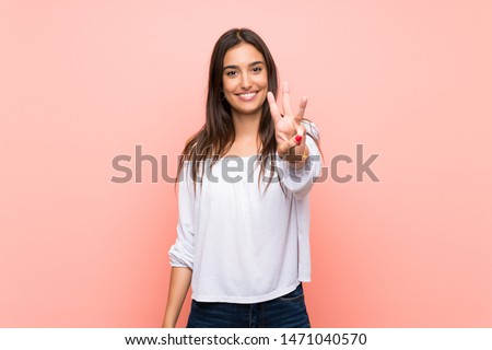 Young woman over isolated pink background happy and counting three with fingers Royalty-Free Stock Photo #1471040570