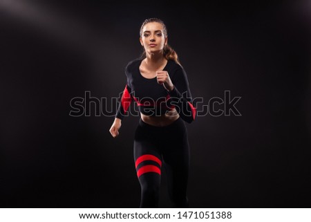 Strong athletic woman sprinter, running on black background wearing in the sportswear. Fitness and sport motivation. Runner concept with copy space.