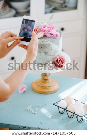 A girl photographs a beautiful cake decorated with roses for her food blog