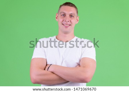Portrait of happy young man smiling with arms crossed