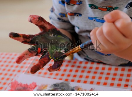 Toddler hands messy painting with brush