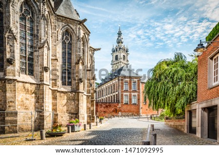 Cobbled street with church and belfry tower in Walloon city center of Mons, Hainaut, Belgium. Royalty-Free Stock Photo #1471092995