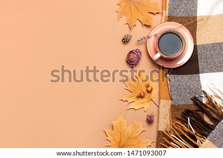 Autumn Flat lay composition. Cup of tea, checkered plaid, autumn dry leaves, roses flowers, orange circle cones decorative pomegranate cinnamon sticks on brown beige background top view. Fall concept 