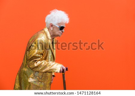 Funny and extravagant senior woman posing on colored background - Youthful old woman in the sixties having fun and partying Royalty-Free Stock Photo #1471128164