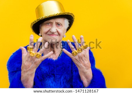 Funny and extravagant senior woman posing on colored background - Youthful old woman in the sixties having fun and partying Royalty-Free Stock Photo #1471128167