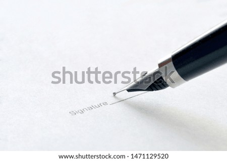 signing a document with an ink pen