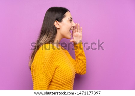 Young woman over isolated purple background shouting with mouth wide open