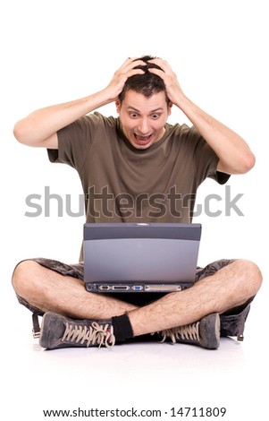 Frustrated young man, holding his head and screaming, sitting with a laptop on white background