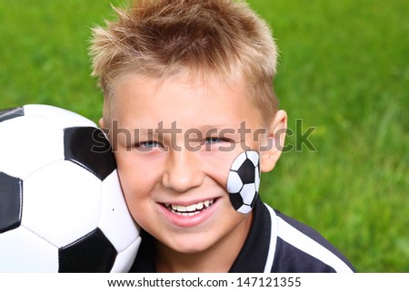 Young happy boy with painted face and soccer ball.