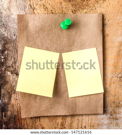 Brown Recycled paper sticky note With green Push Pin and small yellow sticky reminder on wooden vintage background