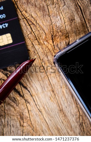 Mobile, Credit Card and pen on old wooden vintage background. Cashless Society Concept pay with Application mobile phone and credit card.Technology payments without cash for convenience