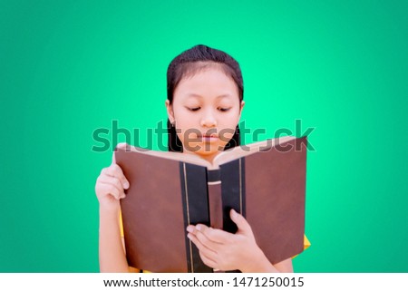 Picture of nerdy schoolgirl reading a book while standing in the studio with green screen background