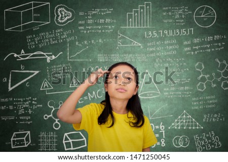 Picture of female elementary school student thinking an idea while standing in the classroom