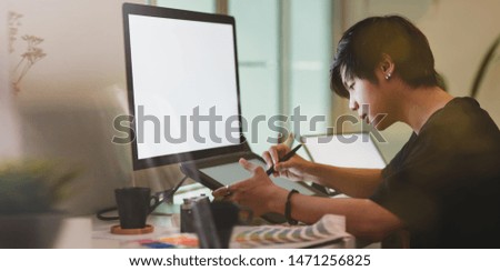 Young professional photographer working on tablet in creative workplace