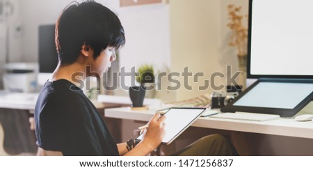 Close-up view of young photographer editing his picture on tablet 