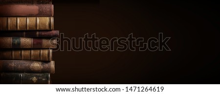 literature / reading concept: banner or header image with stack of antique leather bound books against a dark background Royalty-Free Stock Photo #1471264619