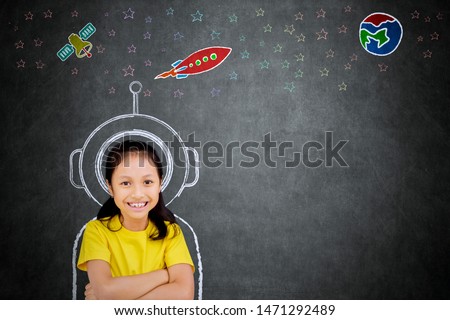 Female elementary school student smiling at the camera while imagining being an astronaut
