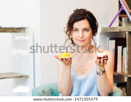 Close up portrait of beautiful woman holding two cakes, one in each hand