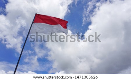 Indonesian flag in the sky. White clouds and blue sky background.    