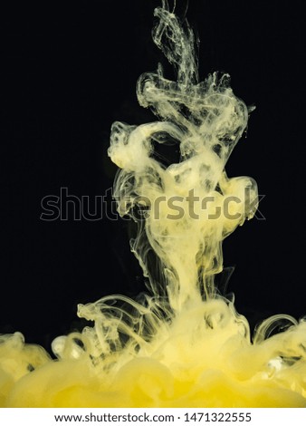 Yellow-white acrylic paint dropped into water, isolated on black background, close up view. Abstract smoke in liquid. Black background for overlays design, screen blending mode layer