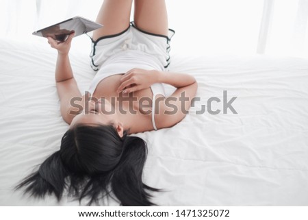 Asia woman lying on the bed in morning with tablet