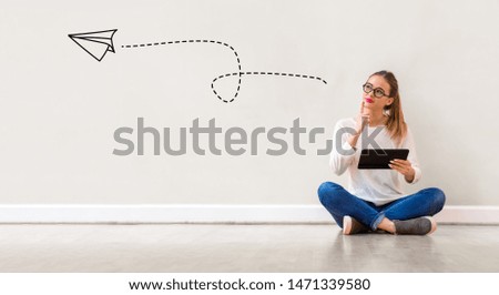 Paper airplane with young woman holding a tablet computer