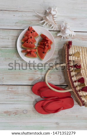 The picture placement the sea concept.Holiday travel. There are red sandals Shells Watermelon and women bag. Wooden background